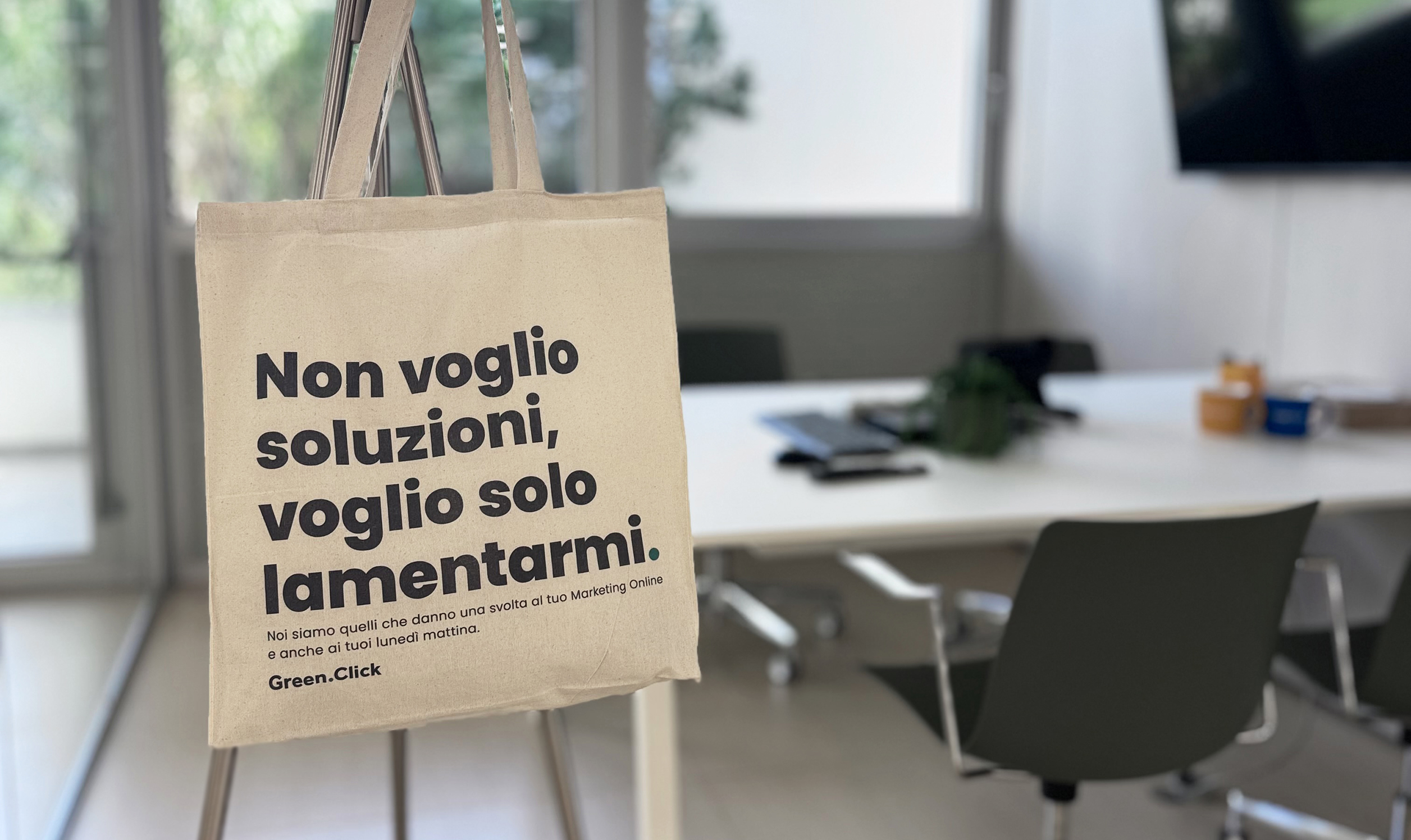 Shopper con scritta ironica “Non voglio soluzioni, voglio solo lamentarmi” in un ufficio moderno, branding Green Click visibile