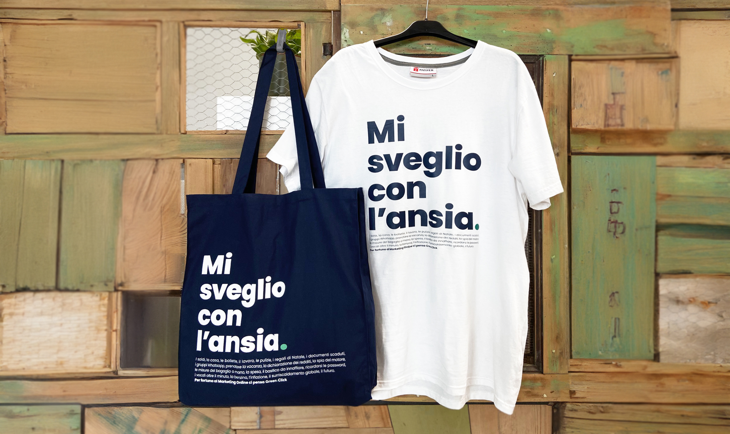 Shopper e t-shirt con scritta "Mi sveglio con l’ansia" esposte su sfondo di legno colorato, gadget promozionali Green Click.
